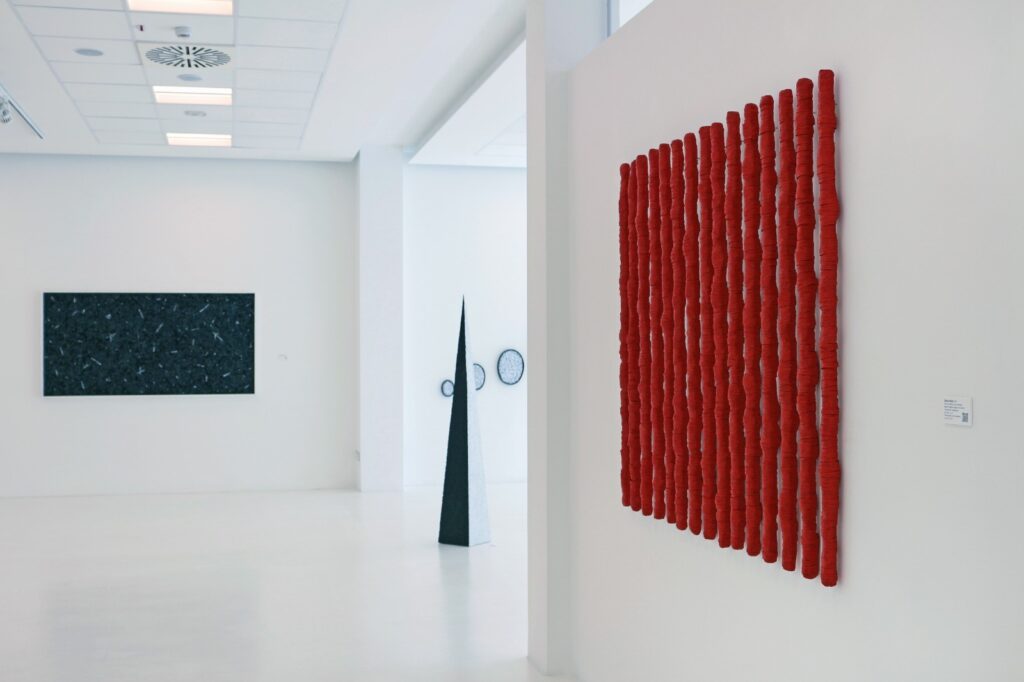 Veduta parziale della mostra personale dal titolo Dare forma ai pensieri, a cura di Ermanno Tedeschi, in collaborazione con Aurora Penne e Ellebi galleria d'arte presso il Museo Officina della Scrittura di Torino. Lo scatto documenta l'allestimento nello spazio espositivo bianco con diverse opere e in primo piano l'opera senza titolo rosso realizzate dall'artista Giovanni Fava.