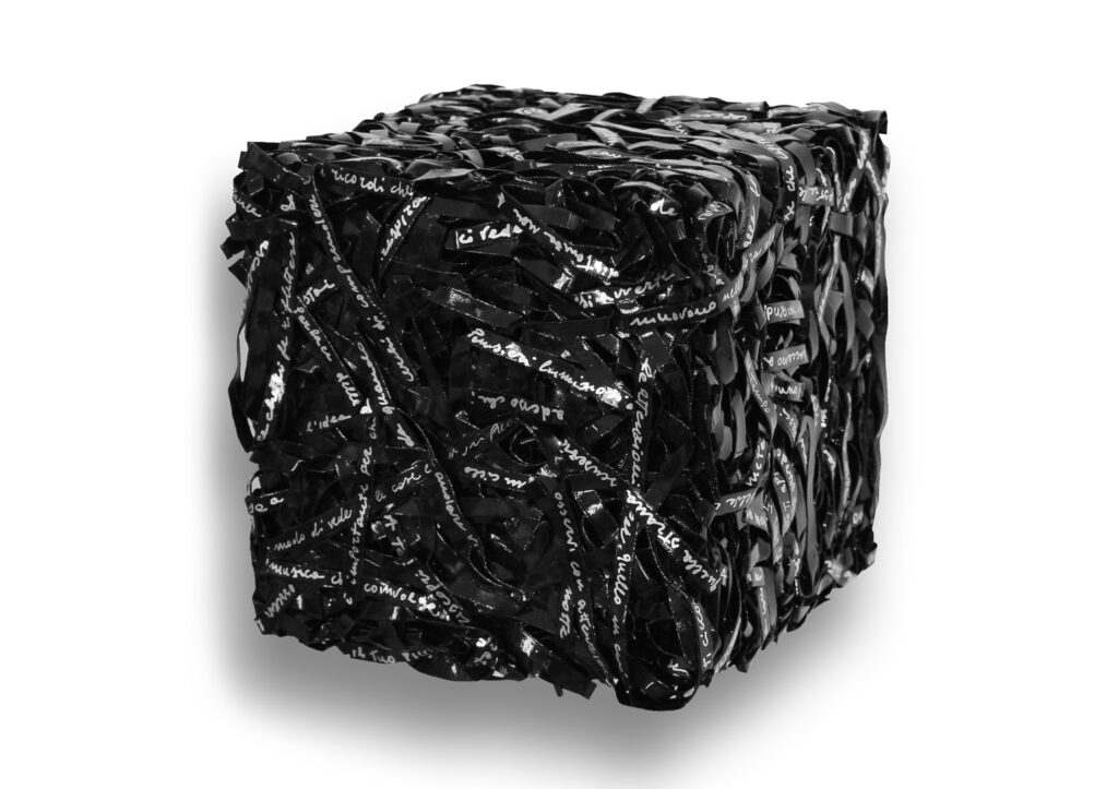 Parole in cubo 2017, scultura e opera d'arte contemporanea a tecnica mista di cm 20 x 20 x 20. L'opera si sviluppa tridimensionalmente a forma di cubo regolare, composta da un fitto e compatto intreccio materico di strisce di carta nere con scritte e grafie manuali color argento. Opera realizzata dall'artista Giovanni Fava.