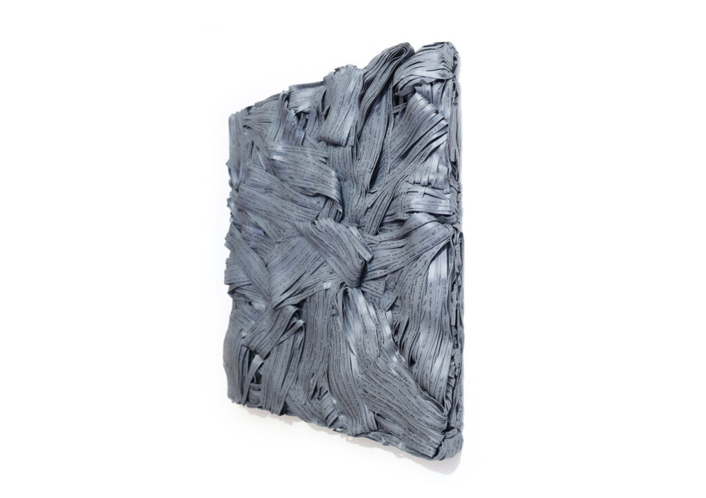 Pensieri grigi 2019, opera d'arte contemporanea a tecnica mista di cm 46 x 51, collezione privata. La foto mostra l'opera in visione laterale per evidenziare lo spessore del quadro a parete, interamente formato da matasse stratificate di carte scritte distrutte e accumulate di colore grigio. Opera realizzata dall'artista Giovanni Fava.