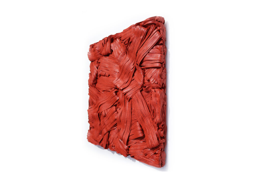 Pensieri rossi 2019, opera d'arte contemporanea a tecnica mista di cm 46 x 51, collezione privata. La foto mostra l'opera in visione laterale per evidenziare lo spessore del quadro a parete, interamente formato da matasse stratificate di carte scritte distrutte e accumulate di colore rosso. Opera realizzata dall'artista Giovanni Fava.