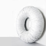 Abyssus 2021, scultura contemporanea a tecnica mista di cm 85 x 85 x 25. L'opera si struttura come un grande volume circolare a forma di toroide o ciambella tridimensionale poggiata a parete, caratterizzata da una superficie interamente fasciata e avvolta in modo radiale da bende di carta bianca dense di frammenti testuali. Realizzazione di Giovanni Fava.