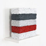 Another word in the brick 2021, opera d'arte contemporanea, tecnica mista su carta e legno. Cinque mattoni con texture di pensieri su carta triturati e compressi poggiano su una mensola bianca. Gli elementi hanno colori misti: bianco, rosso, grigio chiaro e grigio scuro. Opera realizzata dall'artista Giovanni Fava.