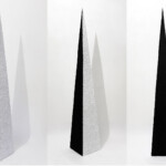 Sul finire 2021, opera d'arte contemporanea, tecnica mista su carta. Visione multipla della forma piramidale allungata con due lati neri e due lati formati da texture materica di parole triturate, realizzata dall'artista Giovanni Fava.